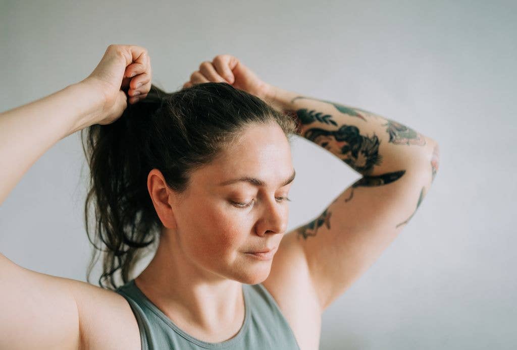 woman pulling hair back into ponytail