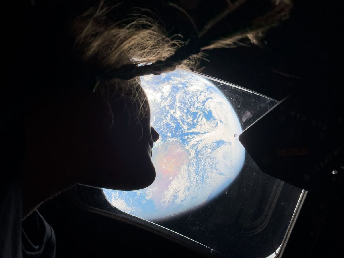 In this handout image provided by NASA, NASA astronaut and Artemis II mission specialist Christina Koch peers out of one of the Orion spacecraft's main cabin windows, looking back at Earth, as the crew travels towards the Moon.