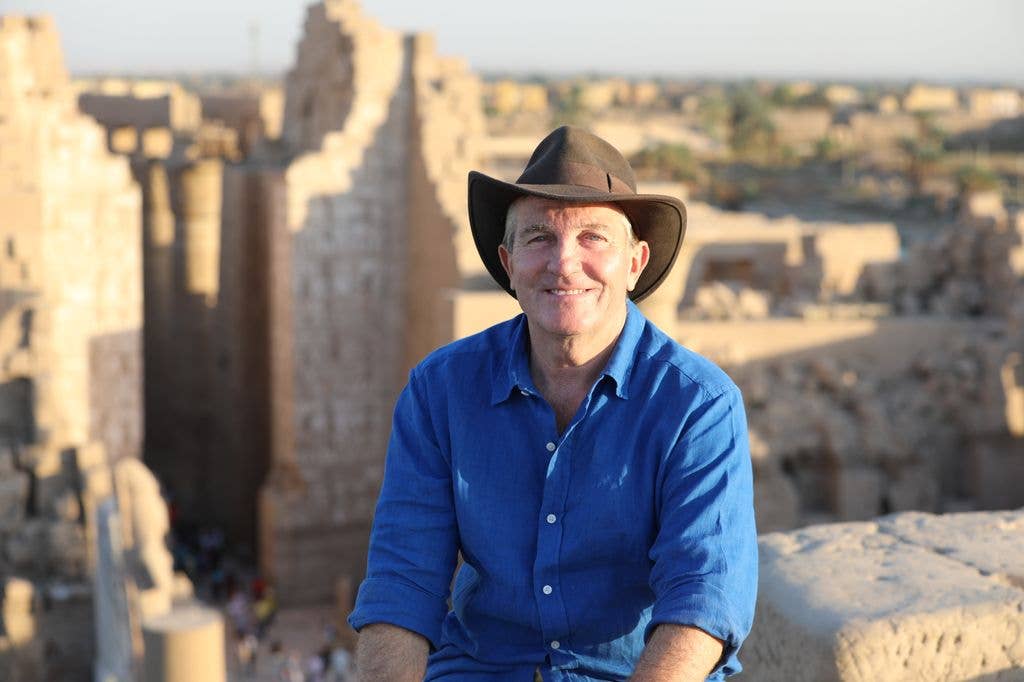 Man in cowboy hat sitting in front of Egyptian tombs