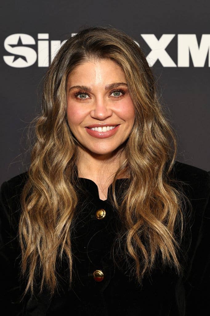 Headshot of Danielle Fishel who looks straight at the camera in a knit buttoned up jacket with loose wavy hair.