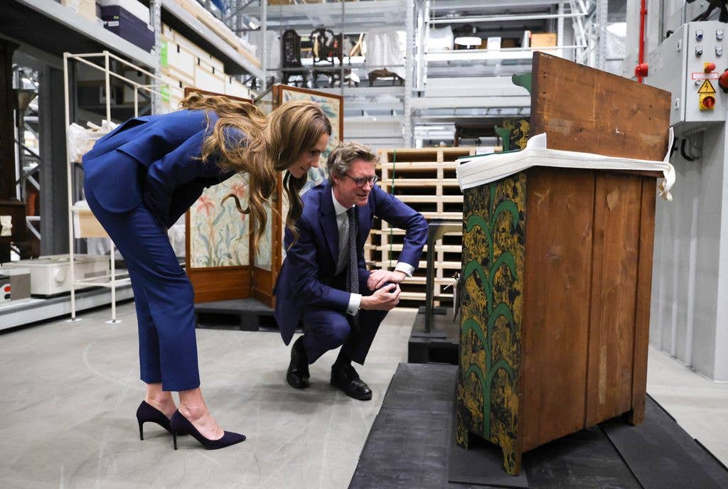 princess kate looking at piece of furniture in blue suit 