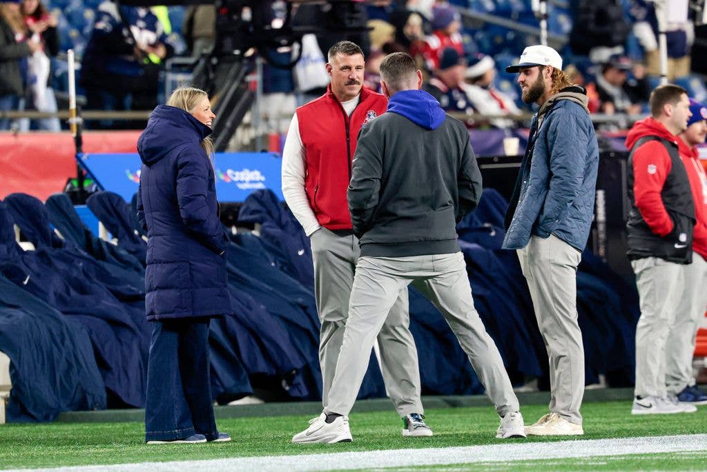 Mike Vrabel of the New England Patriots and his wife Jen speak with New York Giants offensive coordinator Tim Kelly in warm up before a game between the New England Patriots and the New York Giants on December 1, 2025, at Gillette Stadium in Foxborough, Massachusetts