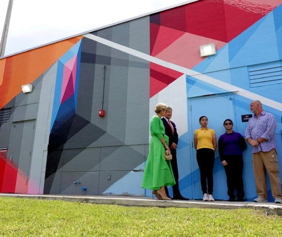 The King and Queen standing in front of one of the colorful murals