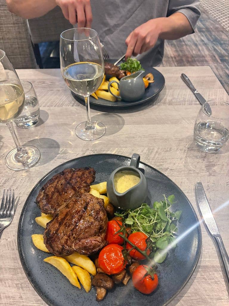 A plate served with steak, chips, blue cheese sauce and some vegetables