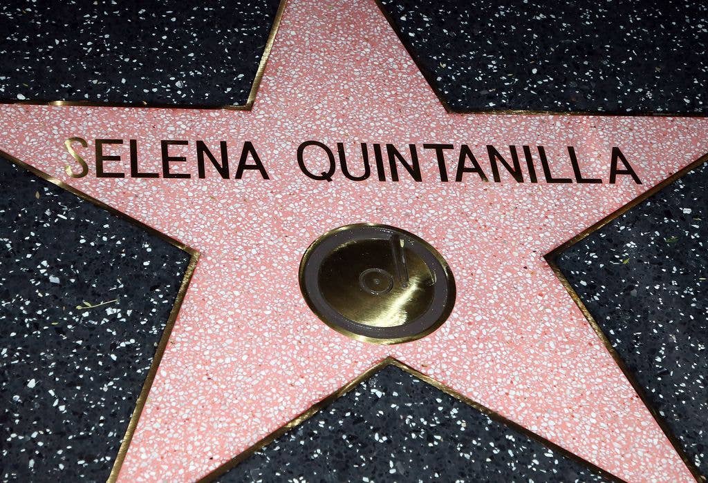 Close up of Selena Quintanilla's Hollywood Star in pink marble on black marble outlined in gold.