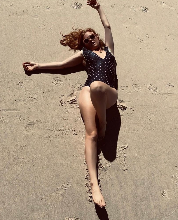 Isla Fisher posing on the sand wearing a polka-dot bikini
