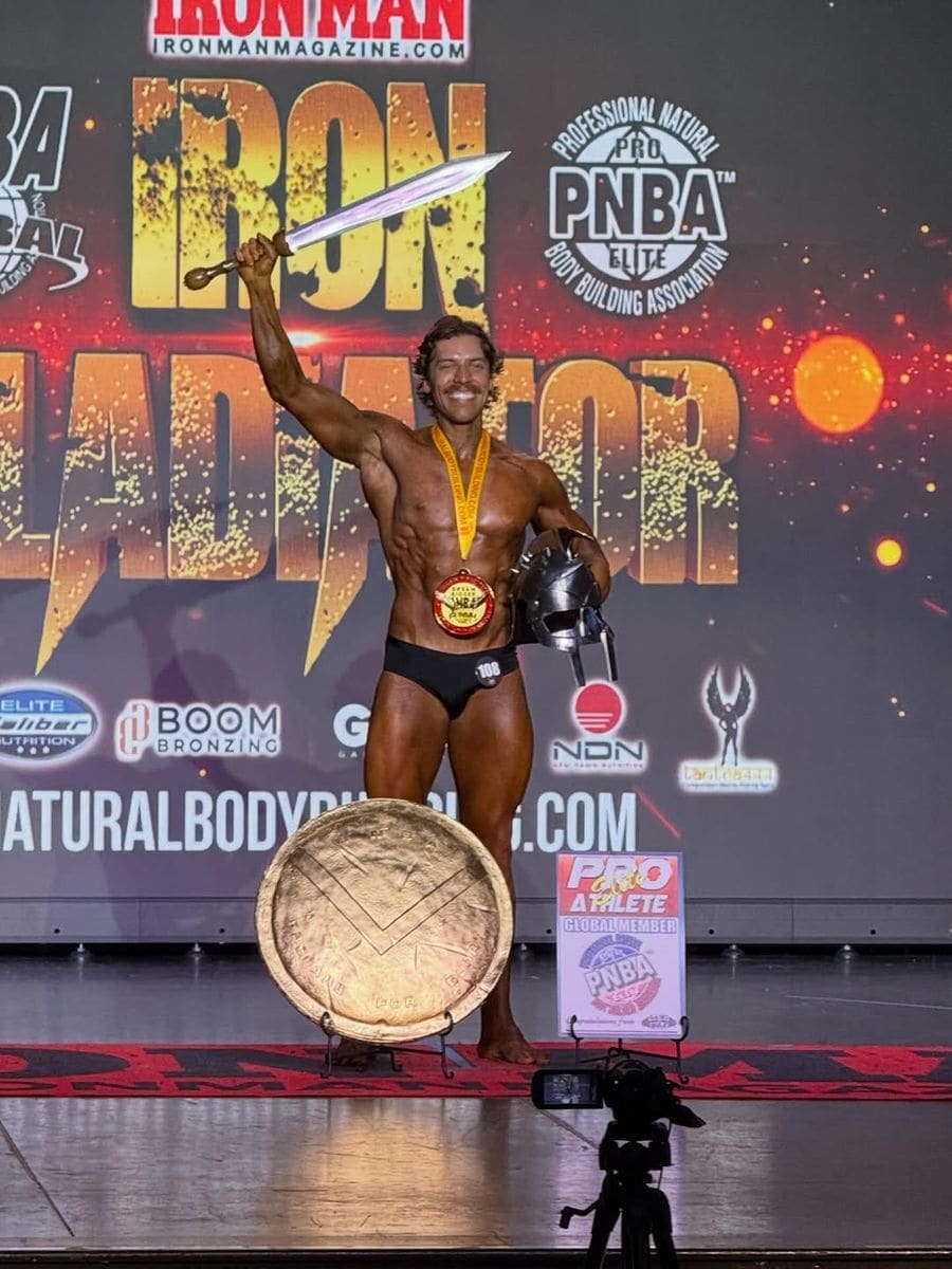 Arnold Schwarzenegger's son Joseph Baena earns his pro card after winning the INBA Iron Gladiator Classic Physique title in just his second competition.