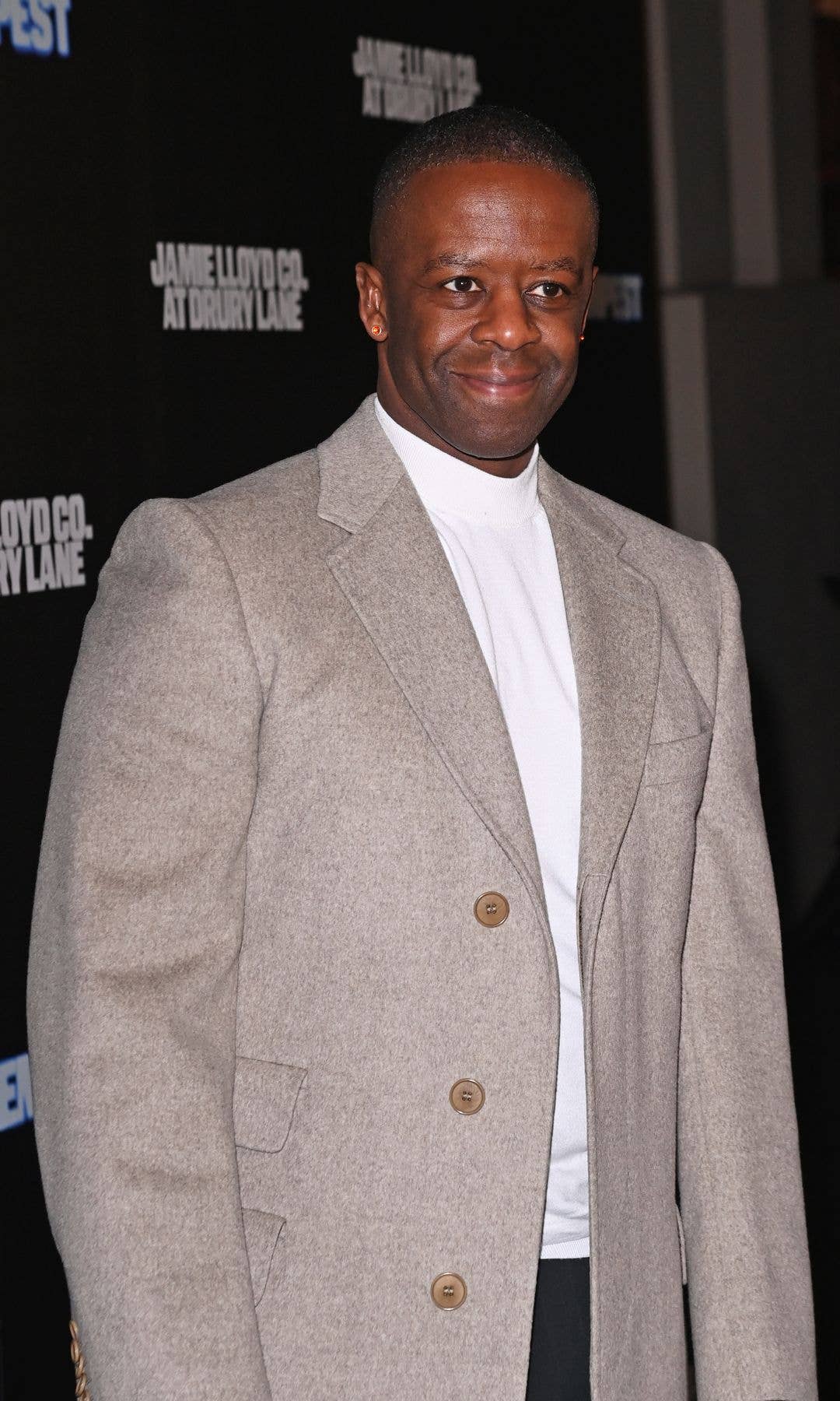Adrian Lester in a tan overcoat at a press performance