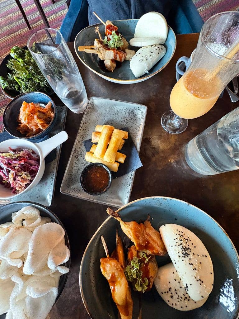 A selection of Chinese inspired food including prawn crackers, chicken skewers, boa buns and crispy kale