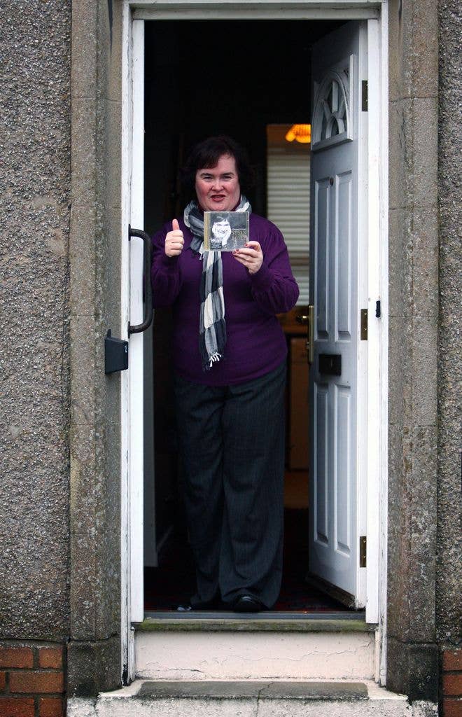 Singer Susan Boyle holding her album standing by her front door
