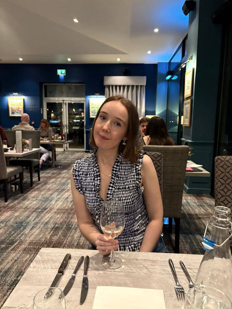 A girl smiling holding a glass of white wine
