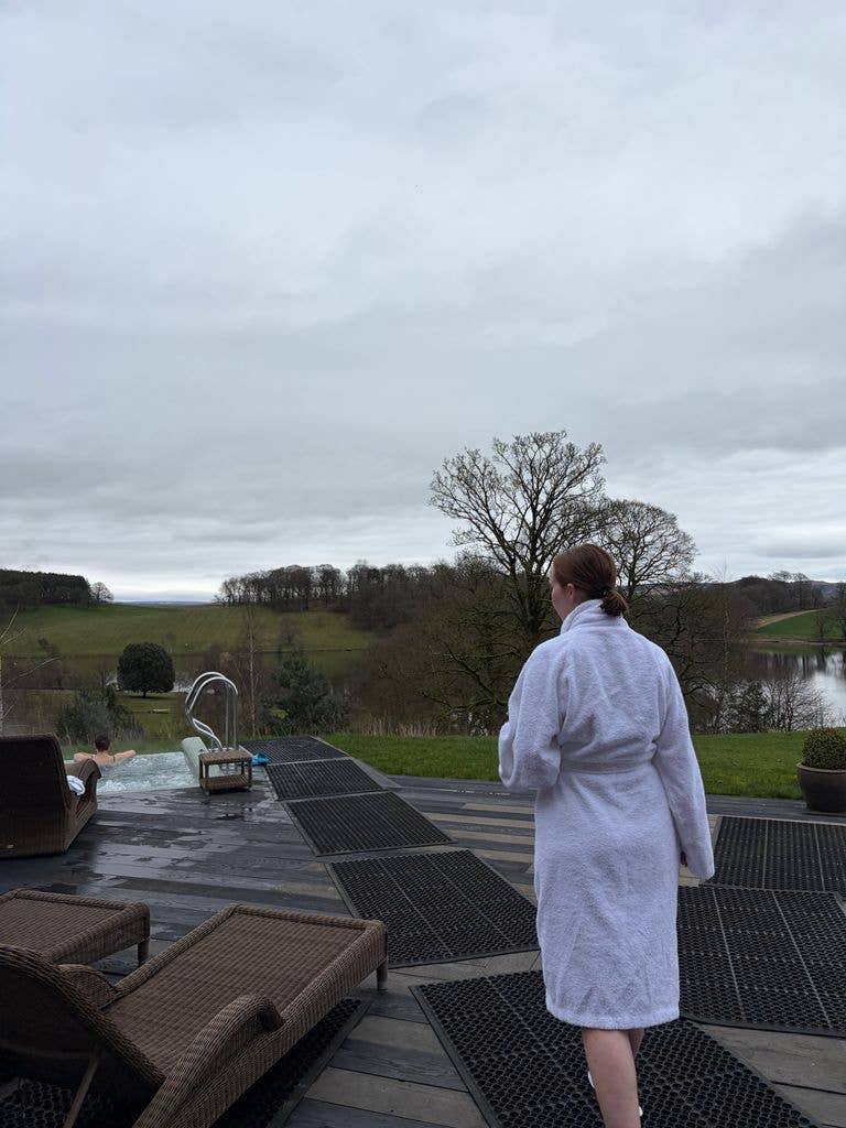 A girl walking in a white spa roba to a jacuzzi