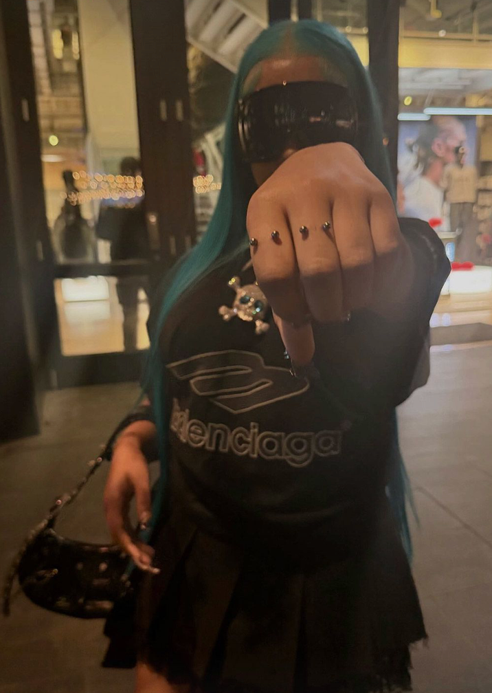 At least three adorn her fingers, with additional studs and spikes decorating her hands and wrists.