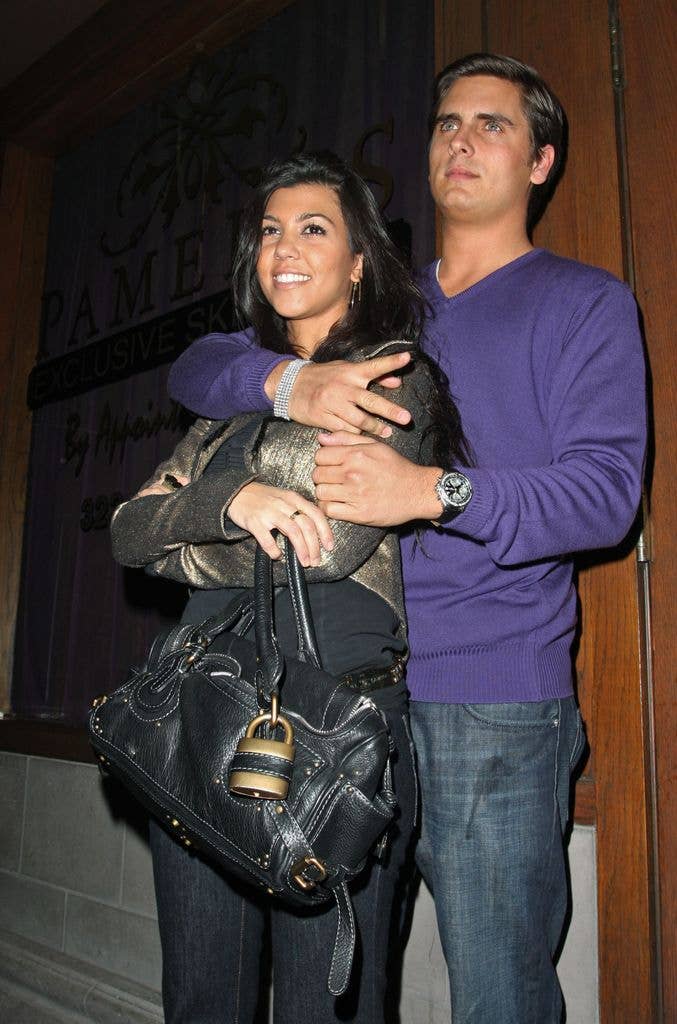 Kourtney Kardashian in leather jacket and Scott Disick in purple jumper hugging