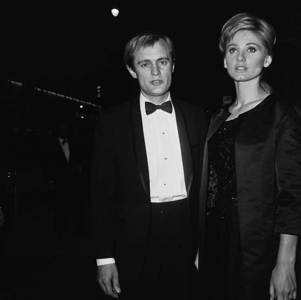 David McCallum in a tux with a bowtie and wife Jill Ireland in a black dress and a long black jacket. 