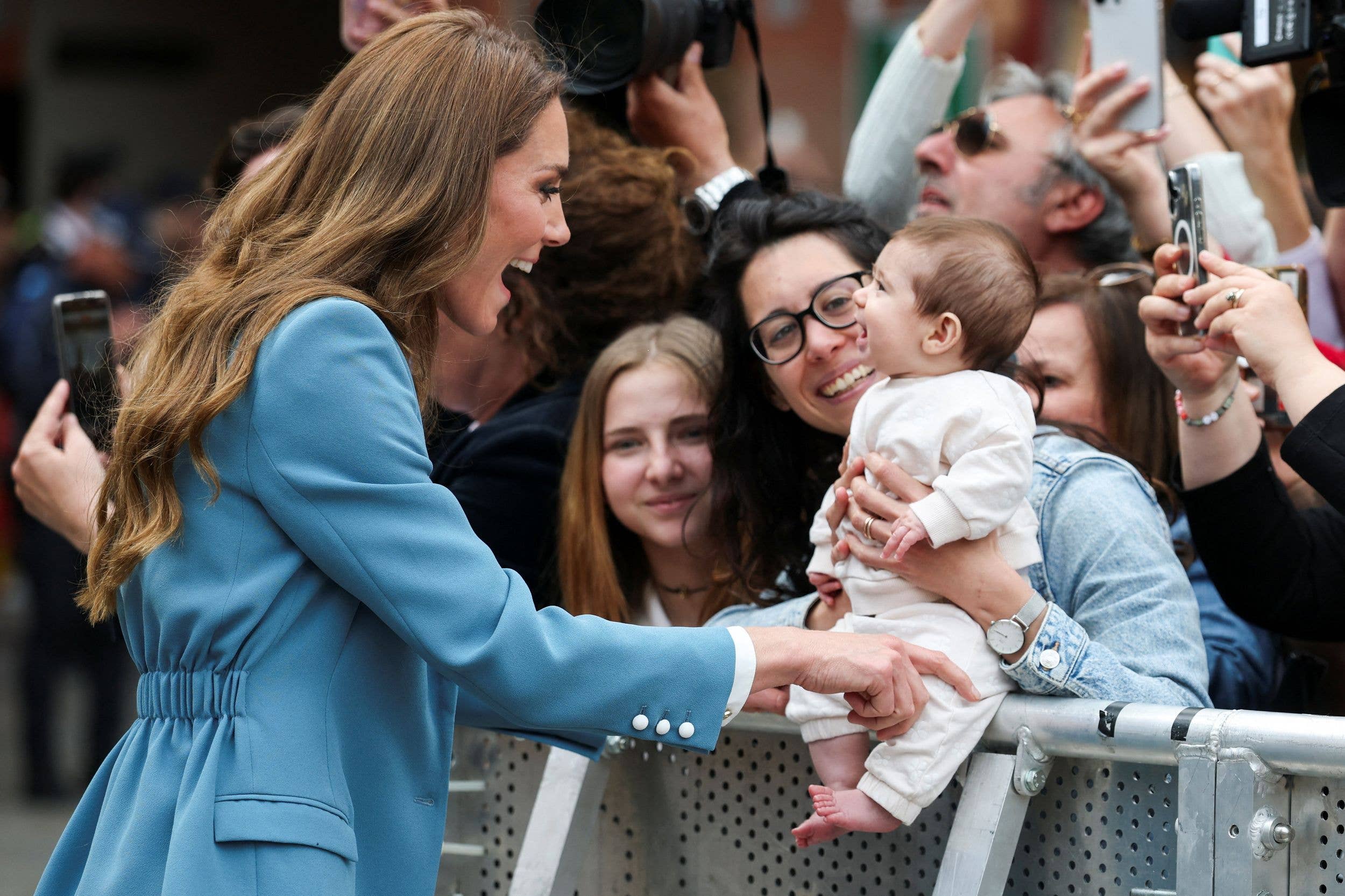 Kate Middleton smiling as she tickles a baby