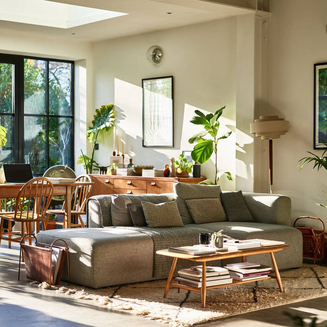 Bright living room with couch, coffee table, dining set, and large windows.