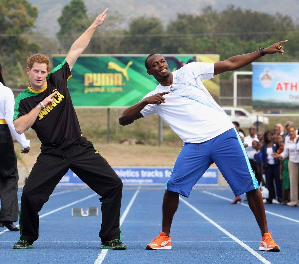 On a race track in 2012, Prince Harry and Usain Bolt both pull the runner's signature pose, bringing one elbow back and pointing their other hand to the sky, leaning back on their right foot. 