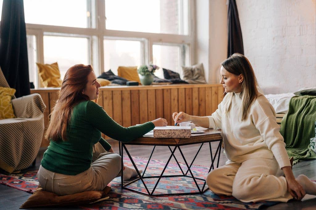 Two women are playing board games at the table. 