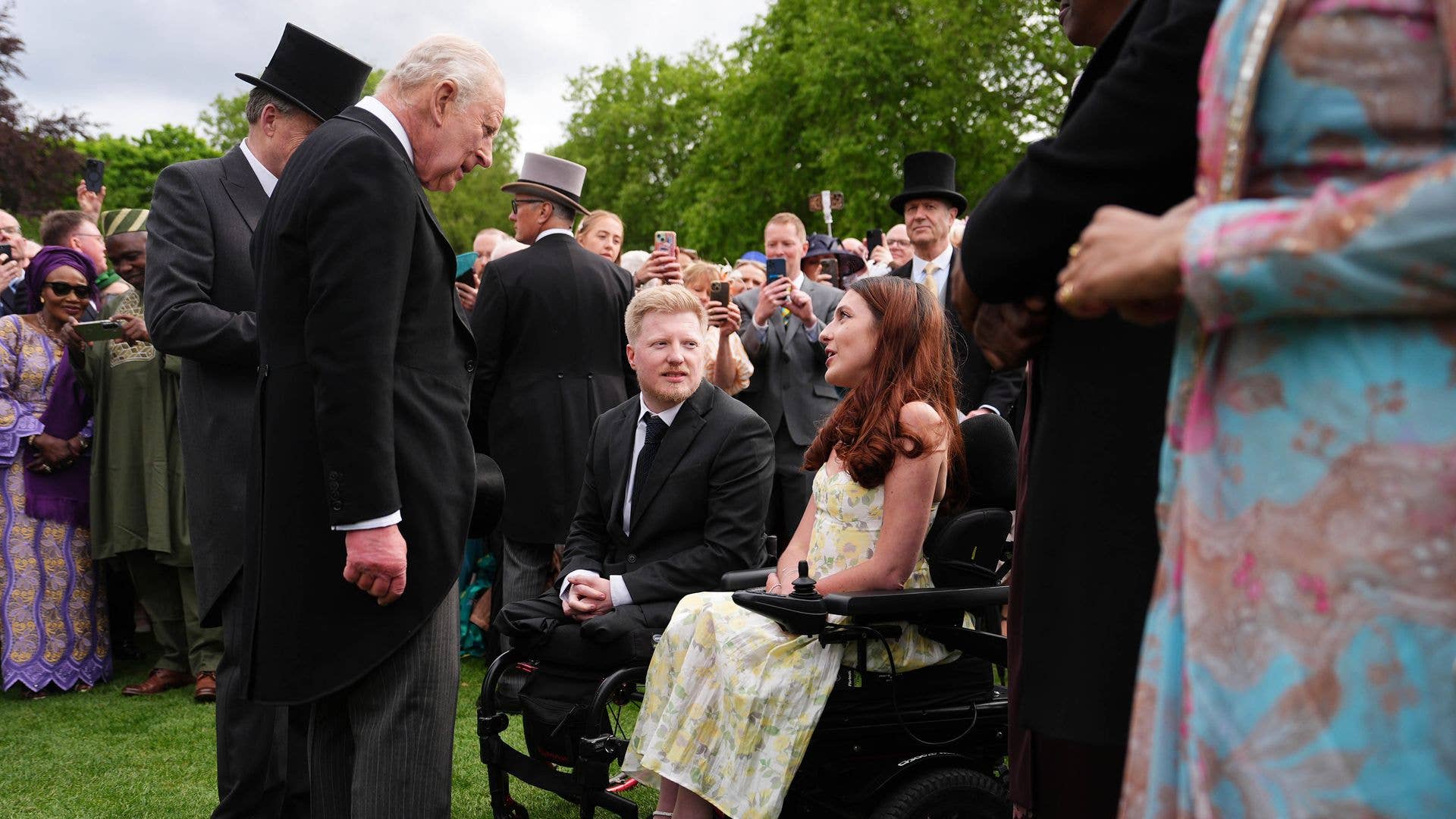 King Charles speaking to two people in wheelchairs