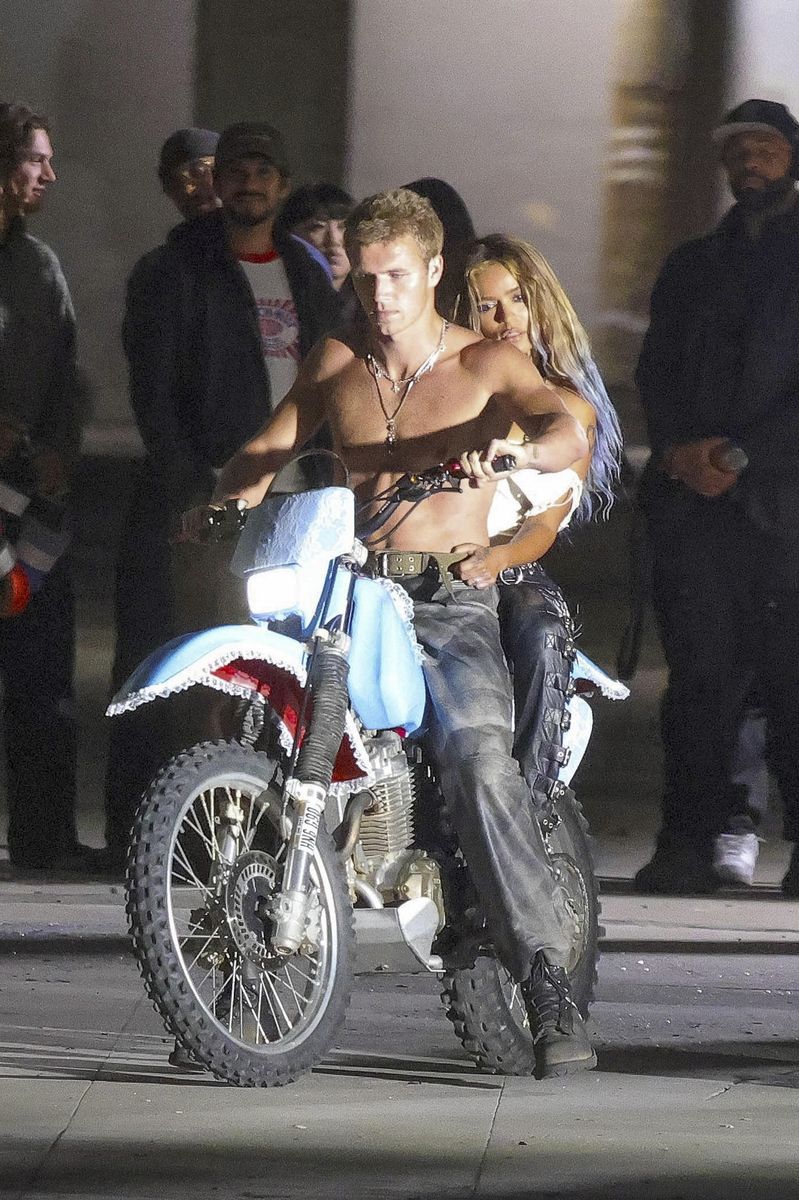 The artist was seen shooting scenes while riding on the back of a motorcycle, holding onto a shirtless male model as production continued in the city.