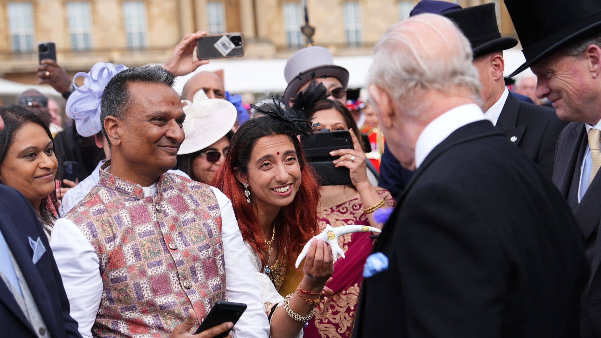 King Charles being presented with a swift figurine at a garden party