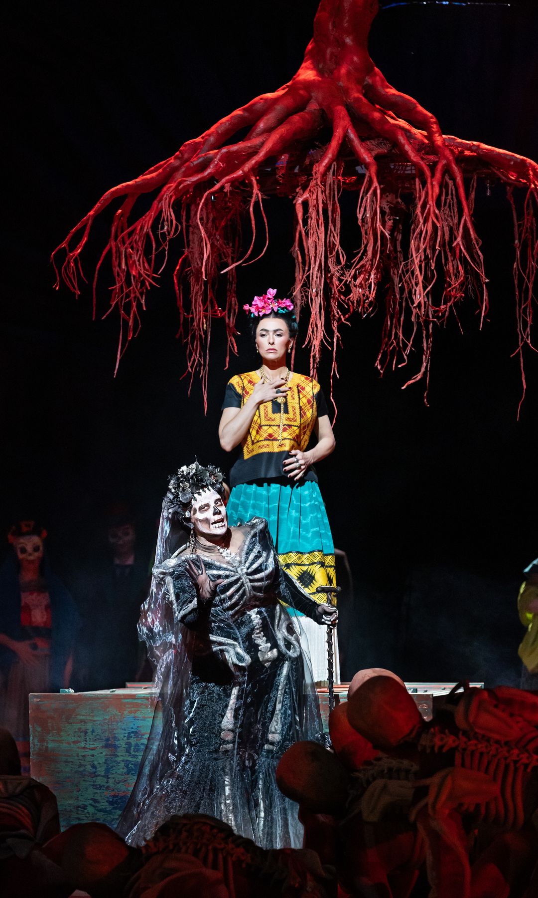 Isabel Leonard and Gabriela Reyes perform beneath a striking crimson tree in El Último Sueño de Frida y Diego