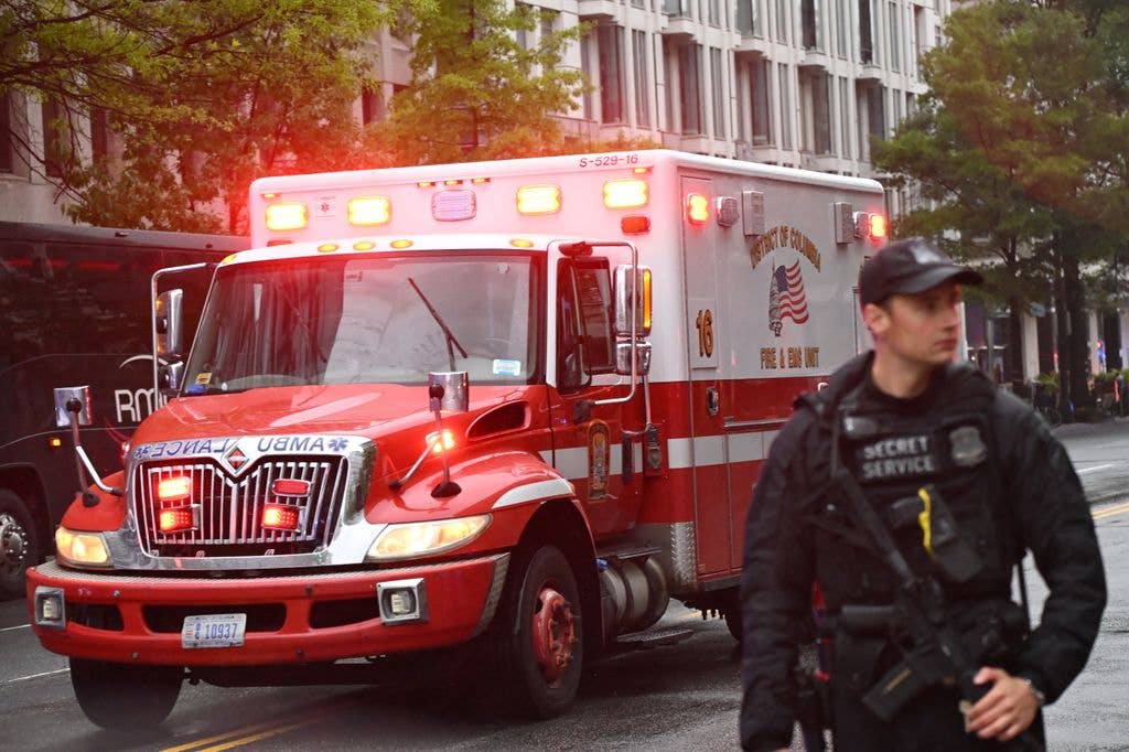 An armed Secret Service agent is seen next to an ambulance near the White House