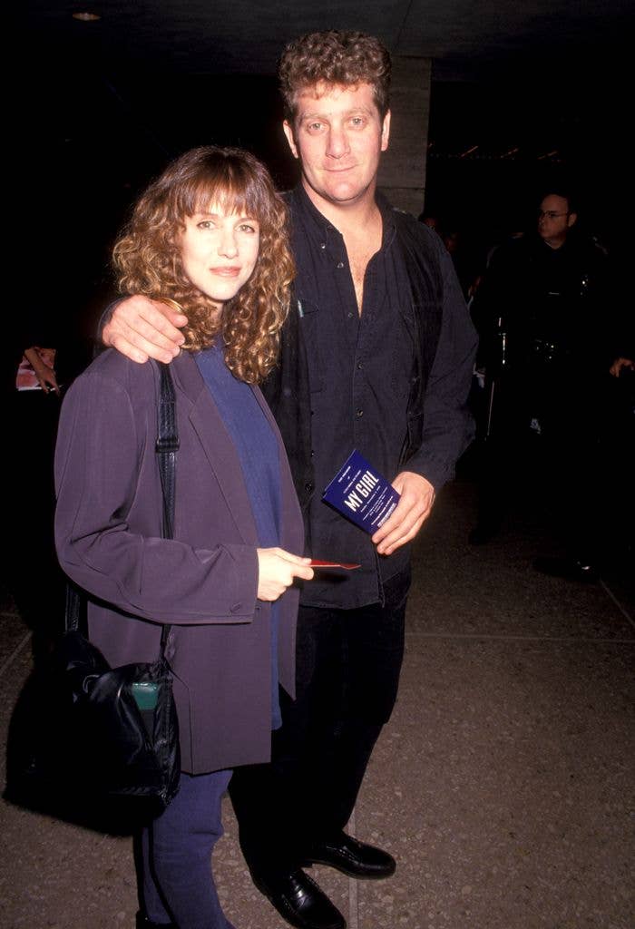 Laraine Newman and Chad Einbinder attend the "My Girl" Century City Premiere. Laraine wears a purple suit and carries a black bag while Chad wears a black suit and holds an arm across her shoulders.