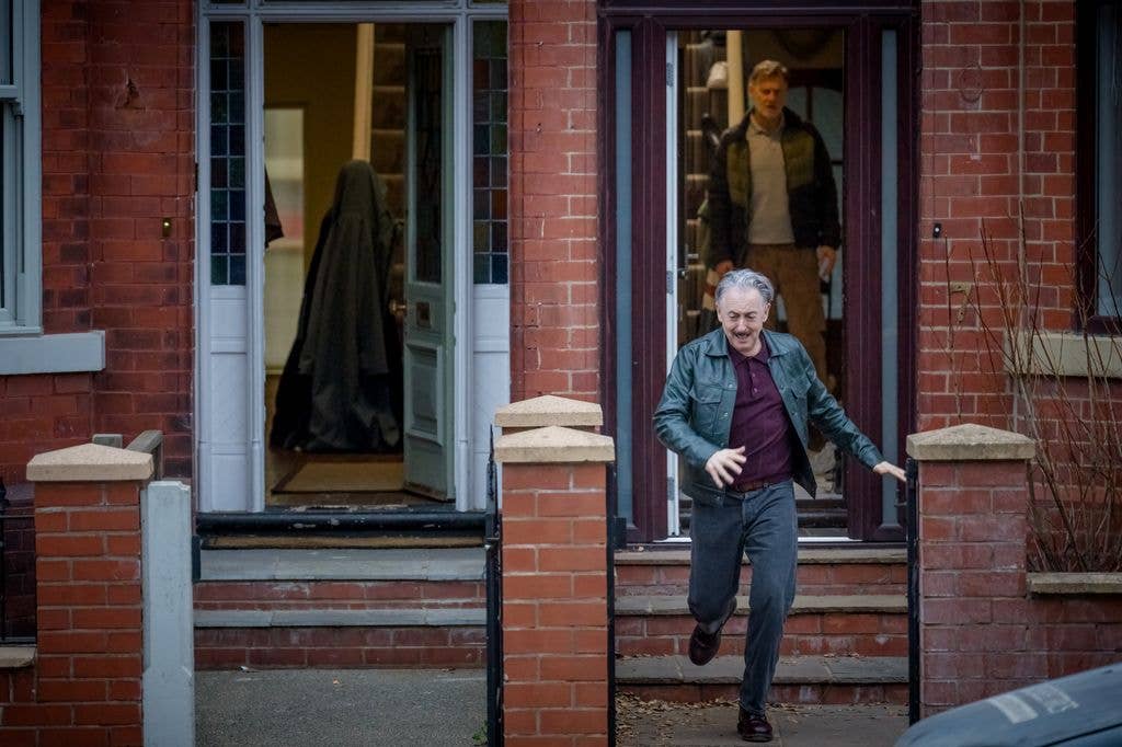 Alan Cumming fleeing a home with David Morrissey standing behind him