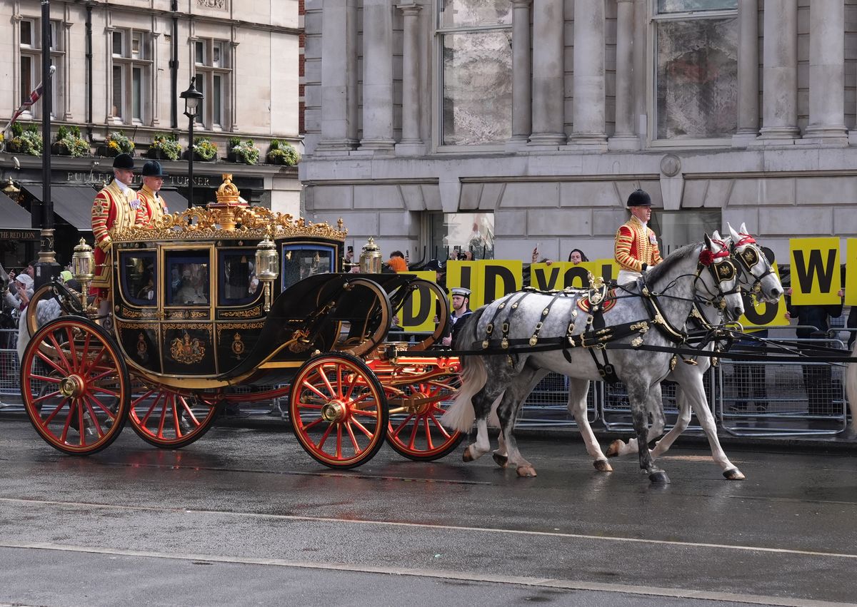 The Irish State Coach, carrying King Charles III and Queen Camilla to the State Opening of Parliament. It traveled past a protest in Westminster, central London