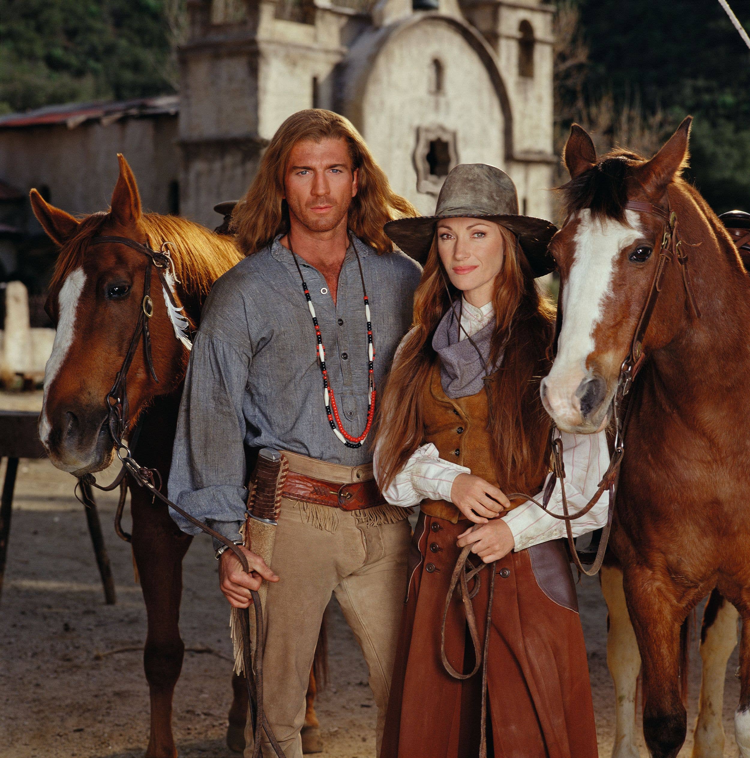 Promotional portrait of British actress Jane Seymour (born Joyce Penelope Wilhelmina Frankenberg), as Dr. Michaela 'Mike' Quinn, and American actor Joe Lando, as Byron Sully, as they pose with horses for the made-for-tv movie 'Dr. Quinn, Medicine Woman: the Movie,' 1999