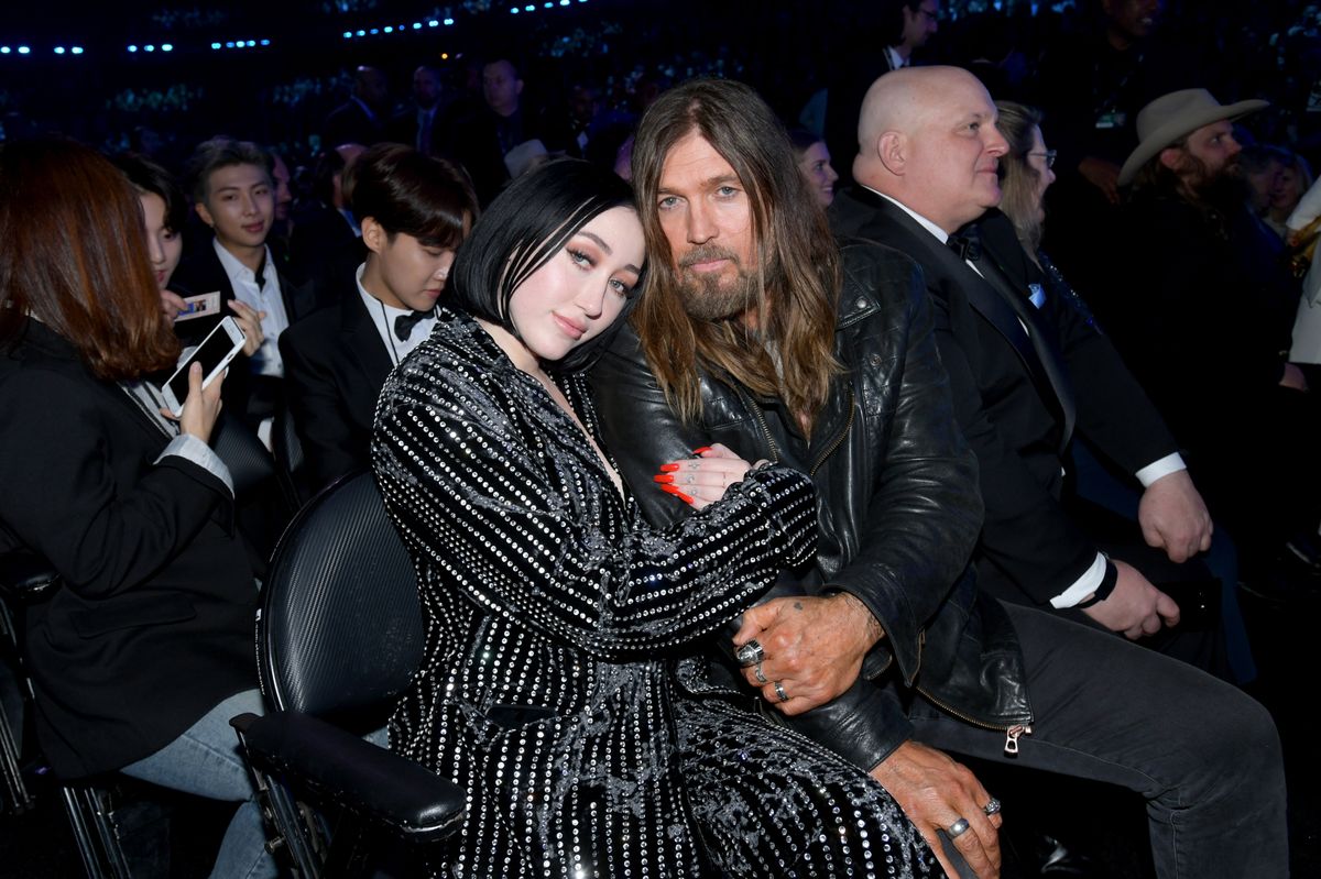 Billy Ray Cyrus and Noah Cyrus sitting together at an event, both smiling.