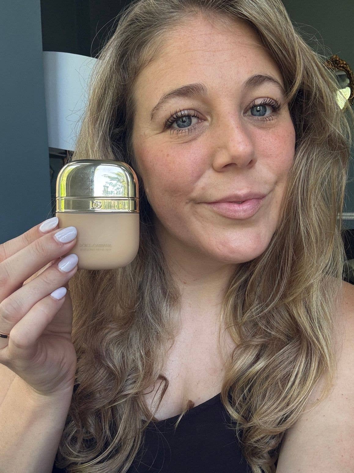 woman holding a makeup product up to the camera 