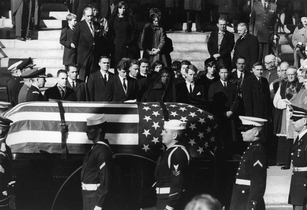 Jacqueline Kennedy, Edward Kennedy and Robert Kennedy stand as the coffin of President John Fitzgerald Kennedy passes them.