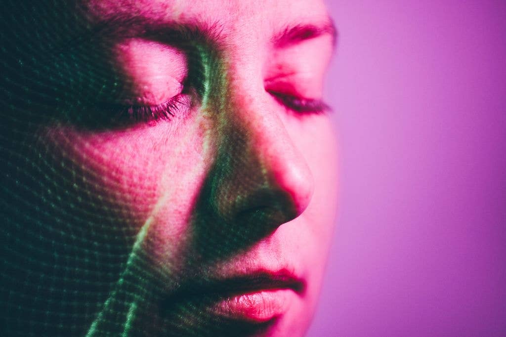Close up of human face with eyes closed and being scanned by biometric identification