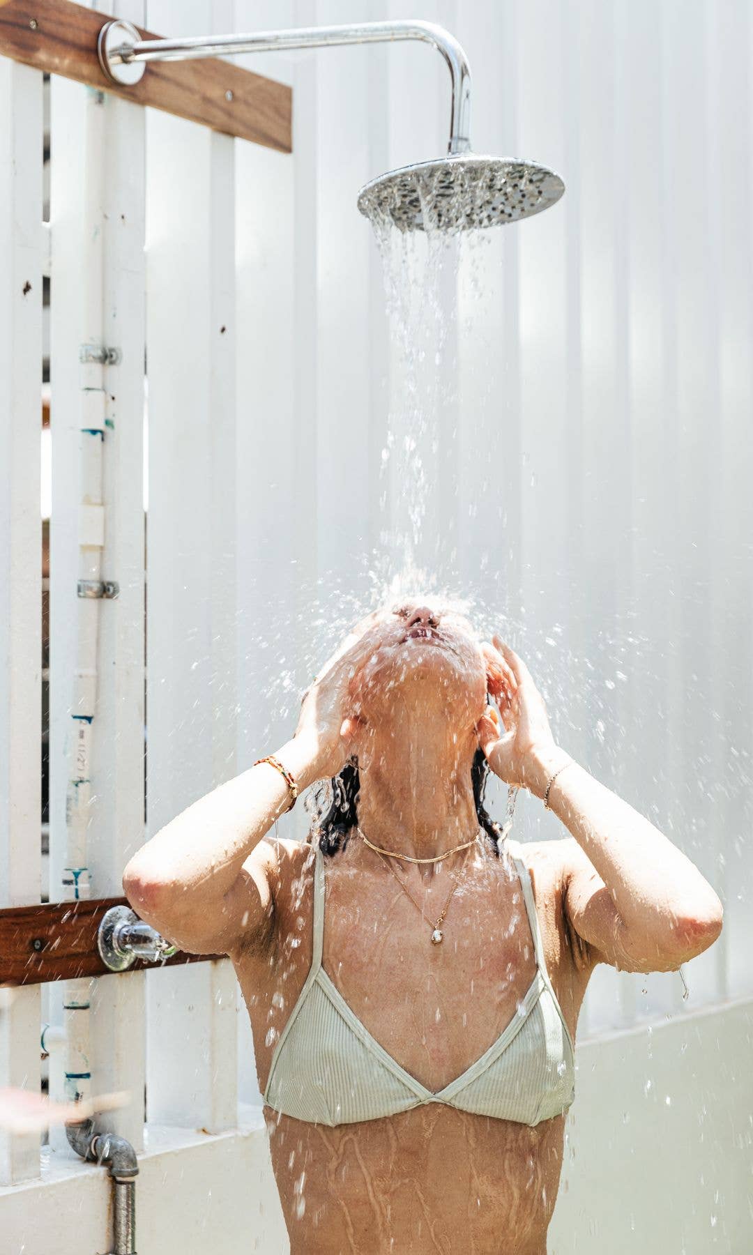 Model turning her face up towards an outdoor shower