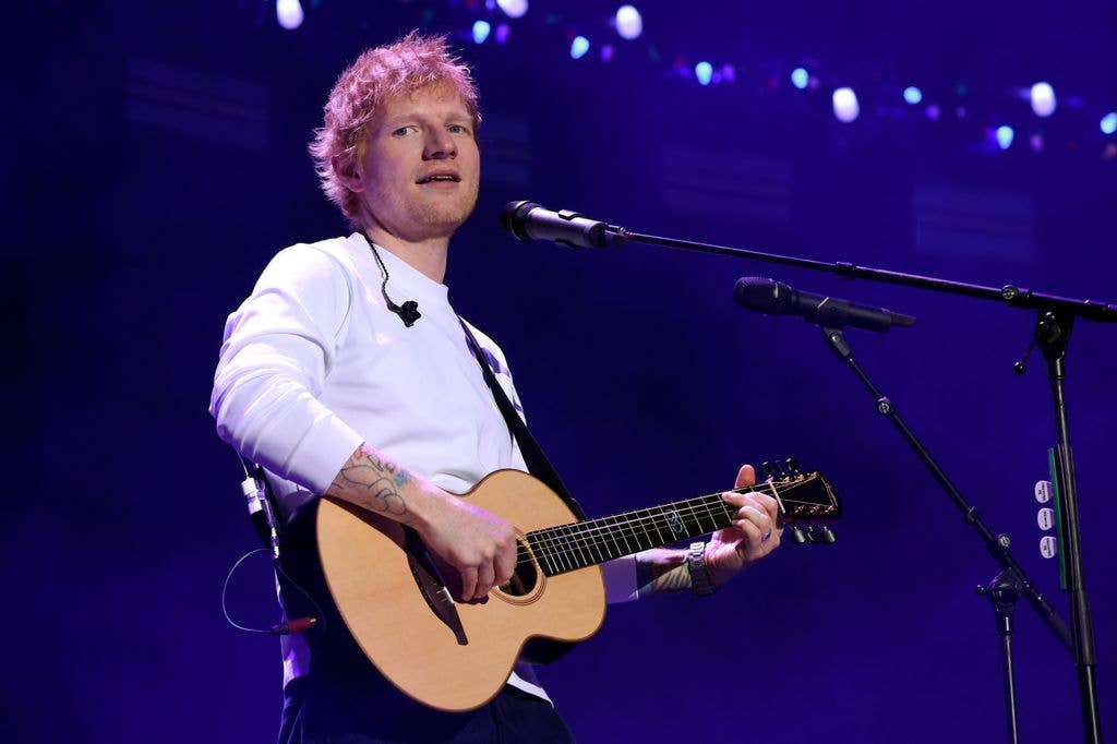 Ed Sheeran in a white tshirt with a guitar, onstage at iHeartRadio z100's Jingle Ball in 2025. 