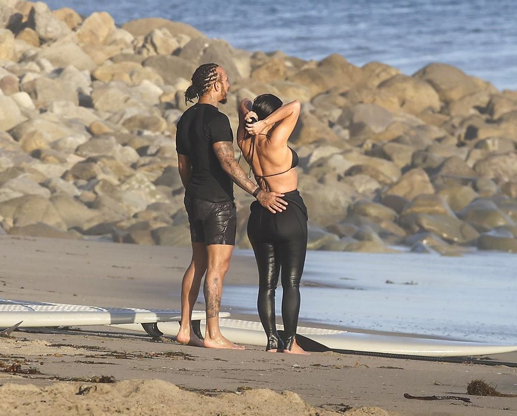 Kim Kardashian and Lewis Hamilton were seen heading to the beach in surf suits, Kim wearing a black bikini top, and spent several hours taking lessons.