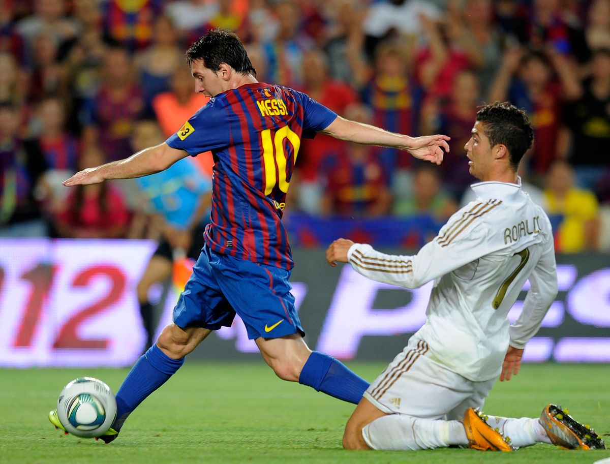 Barcelona's Argentinian forward Lionel Messi (L) scores a goal as he vies with Real Madrid's Portuguese forward Cristiano Ronaldo.
