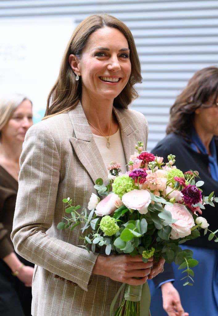 Kate Middleton smiling while holding a bouquet of flowers