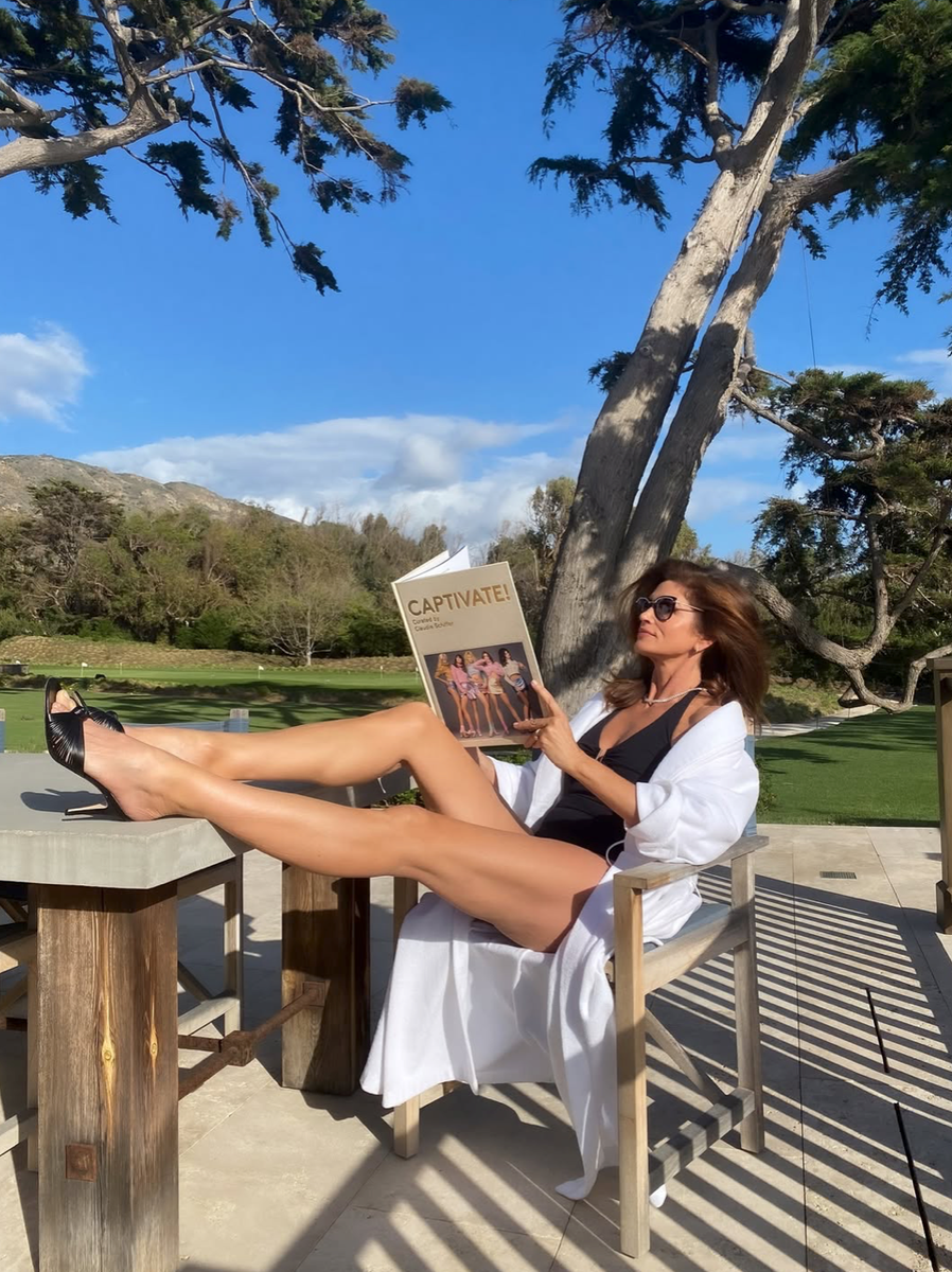 Crawford embraced effortless sophistication with windswept hair, cat-eye sunglasses, and a white robe draped over her shoulders.