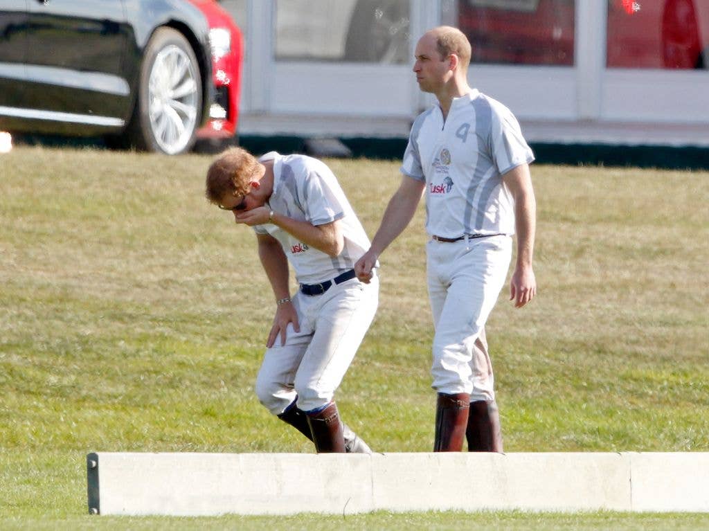 Prince Harry bends as he sneezes next to Prince William at the polo 