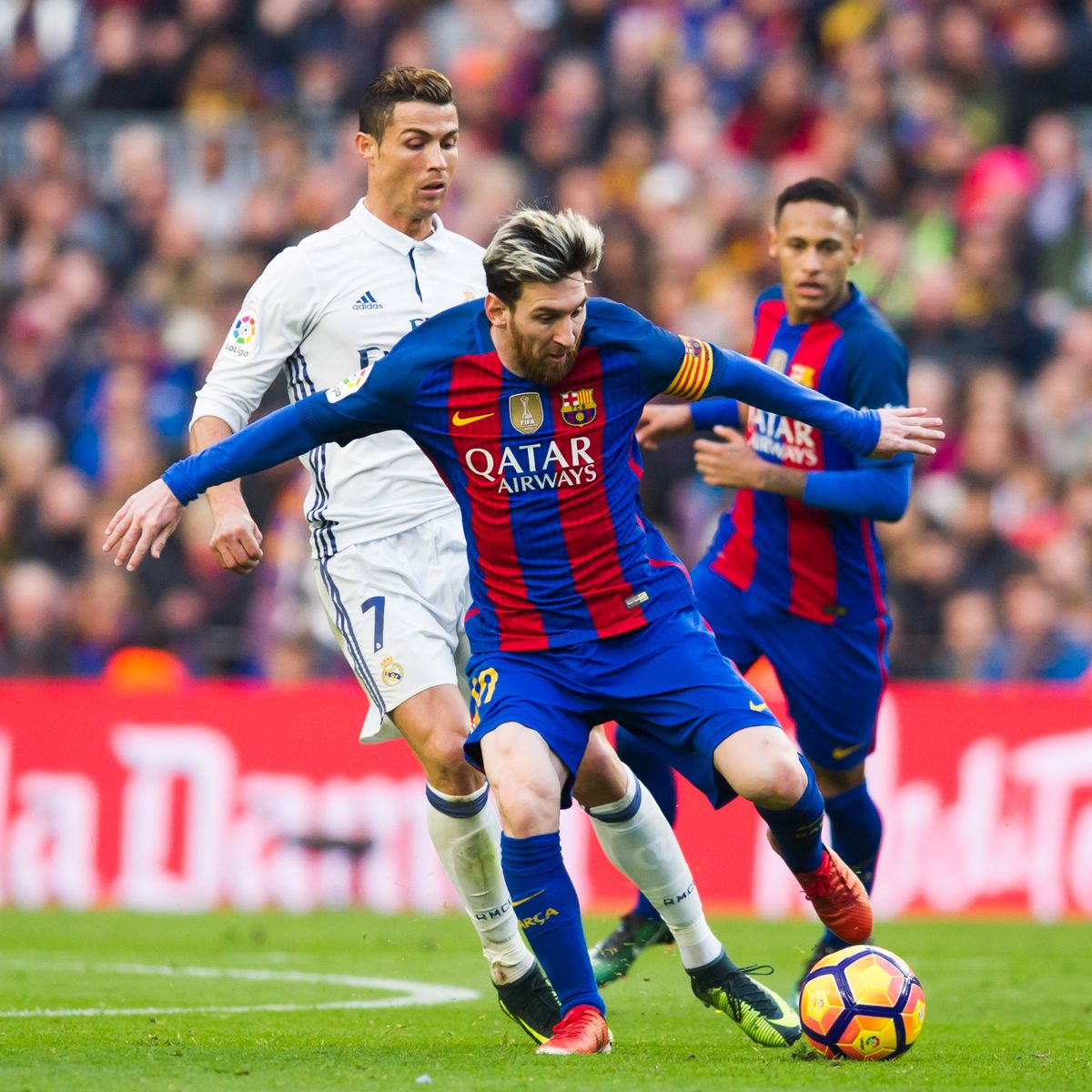 Lionel Messi of FC Barcelona conducts the ball next to Cristiano Ronaldo of Real Madrid CF during the La Liga match