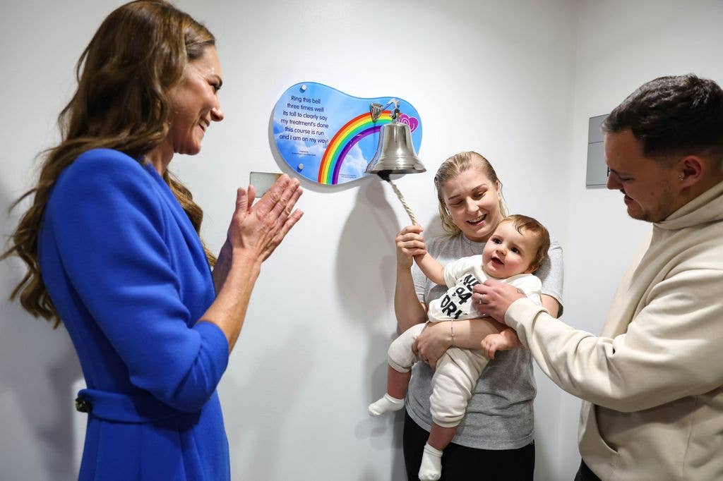 Kate Middleton applauding a woman, who carries a baby, as she rings the bell