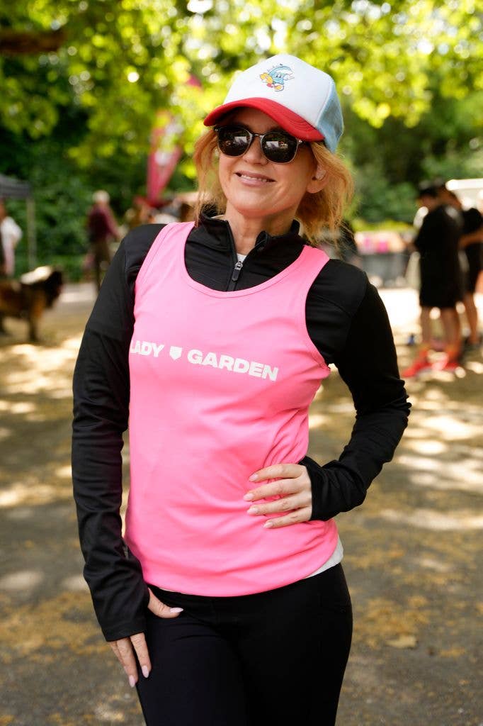 Isla Fisher stands smiling in a park