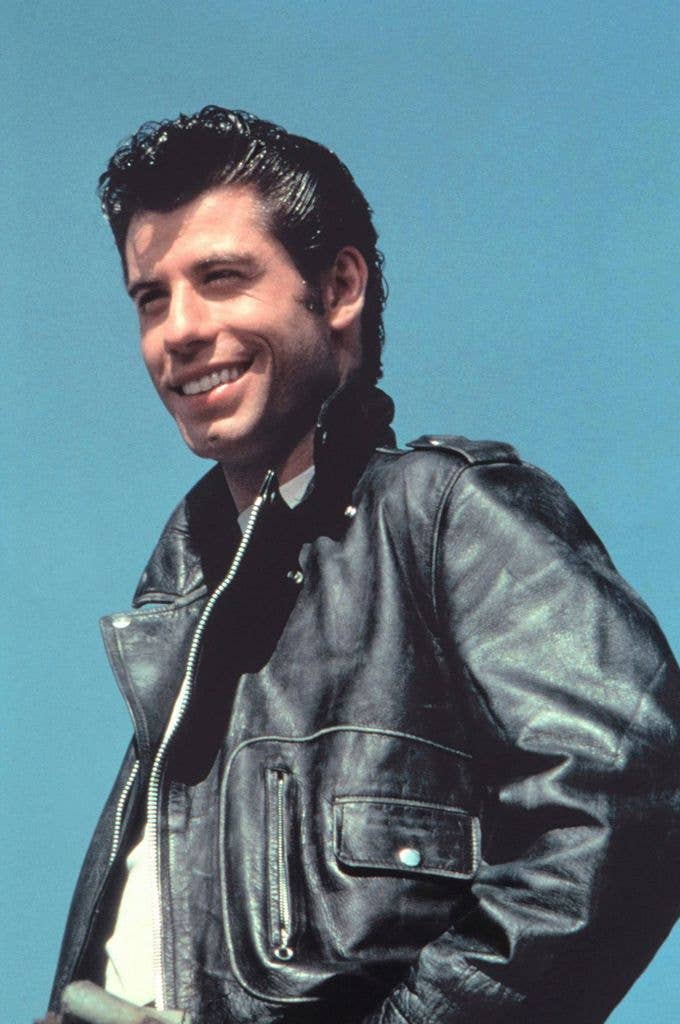 John Travolta on the set of grease in a white tshirt and black leather jacket.