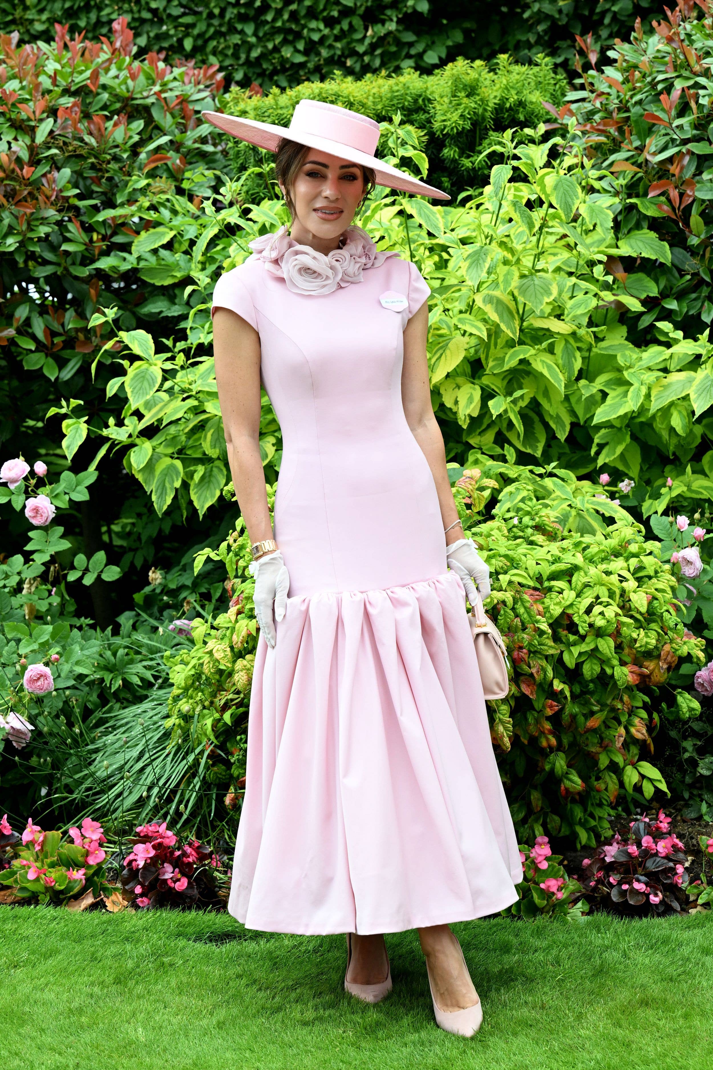 Lydia Millen wears a pale pink midi dress and matching hat, shoes and bag