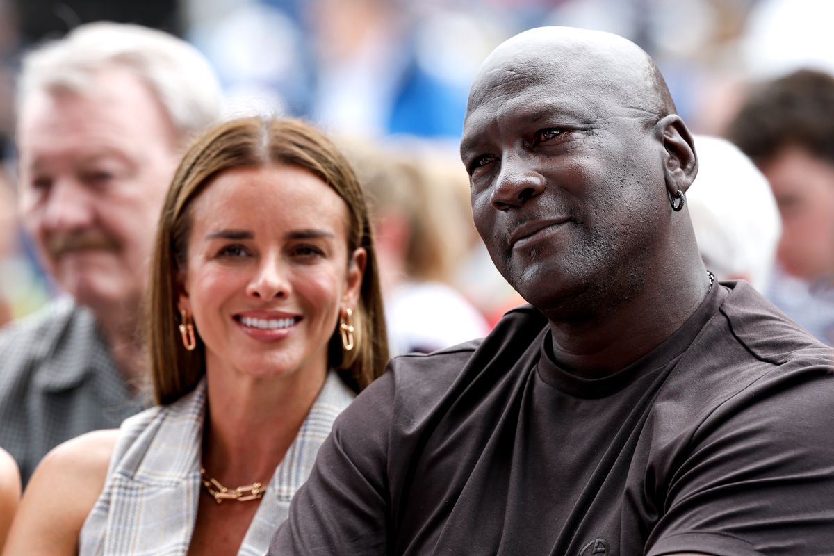 Michael Jordan and a woman sit among a crowd, both smiling.