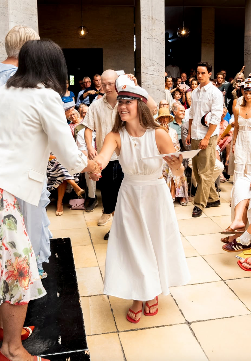 The Danish royal completed her elegant summer look with a traditional graduation cap, layered gold jewelry and bright red flip-flops.